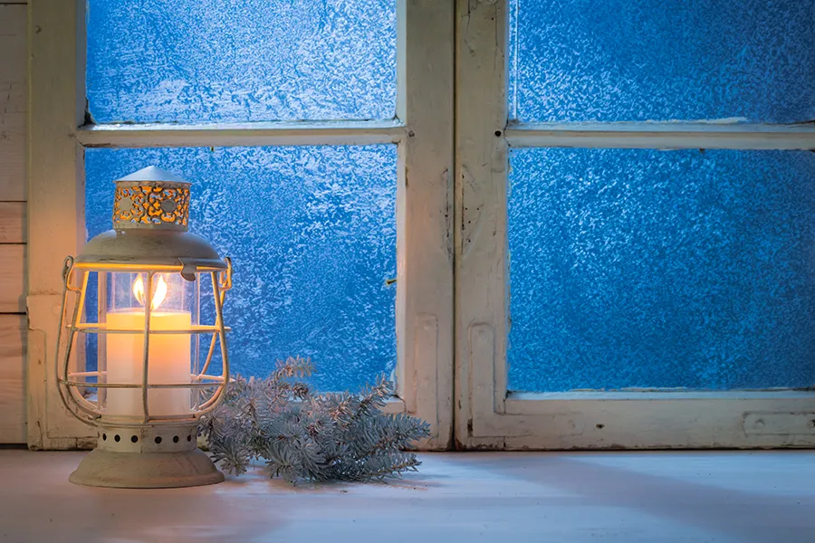 Lantern in front of a blue window.